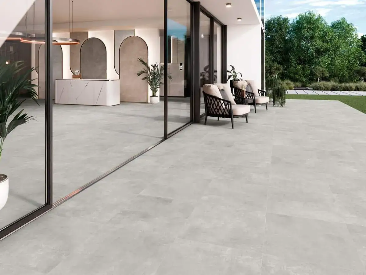 Modern patio con suelo de baldosas grises, ideal para saber como colocar baldosas en el suelo. Muebles de exterior y vegetación.