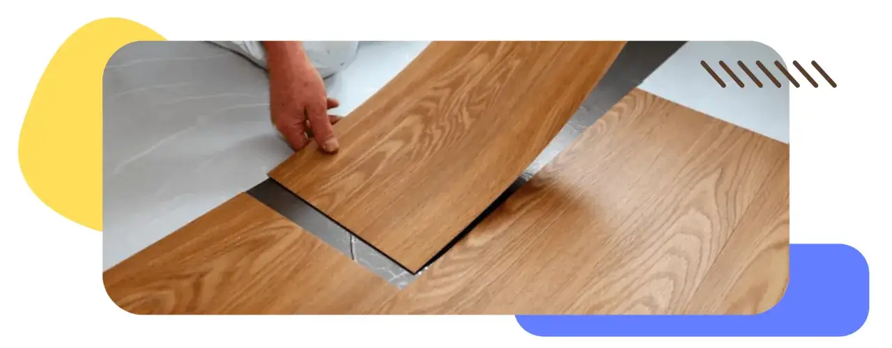 Mano colocando una tabla de suelo vinílico imitación madera sobre otra.