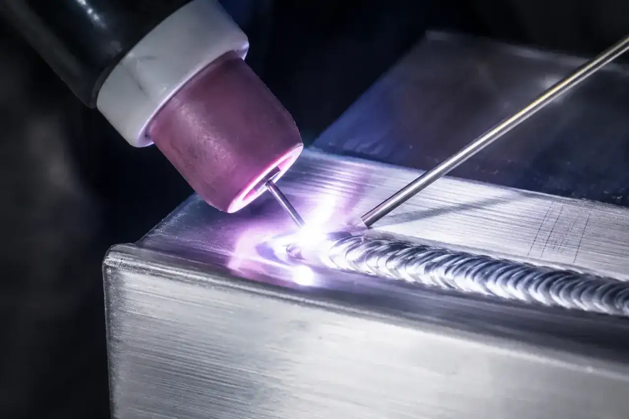 Proceso de soldar acero inoxidable con antorcha TIG, creando un cordón brillante y uniforme.