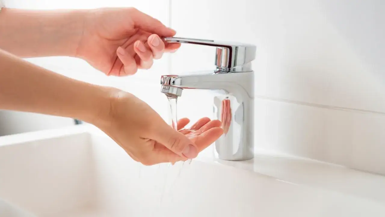 Manos bajo un grifo moderno, el agua fluye con buena presión, ideal para la higiene en casa.