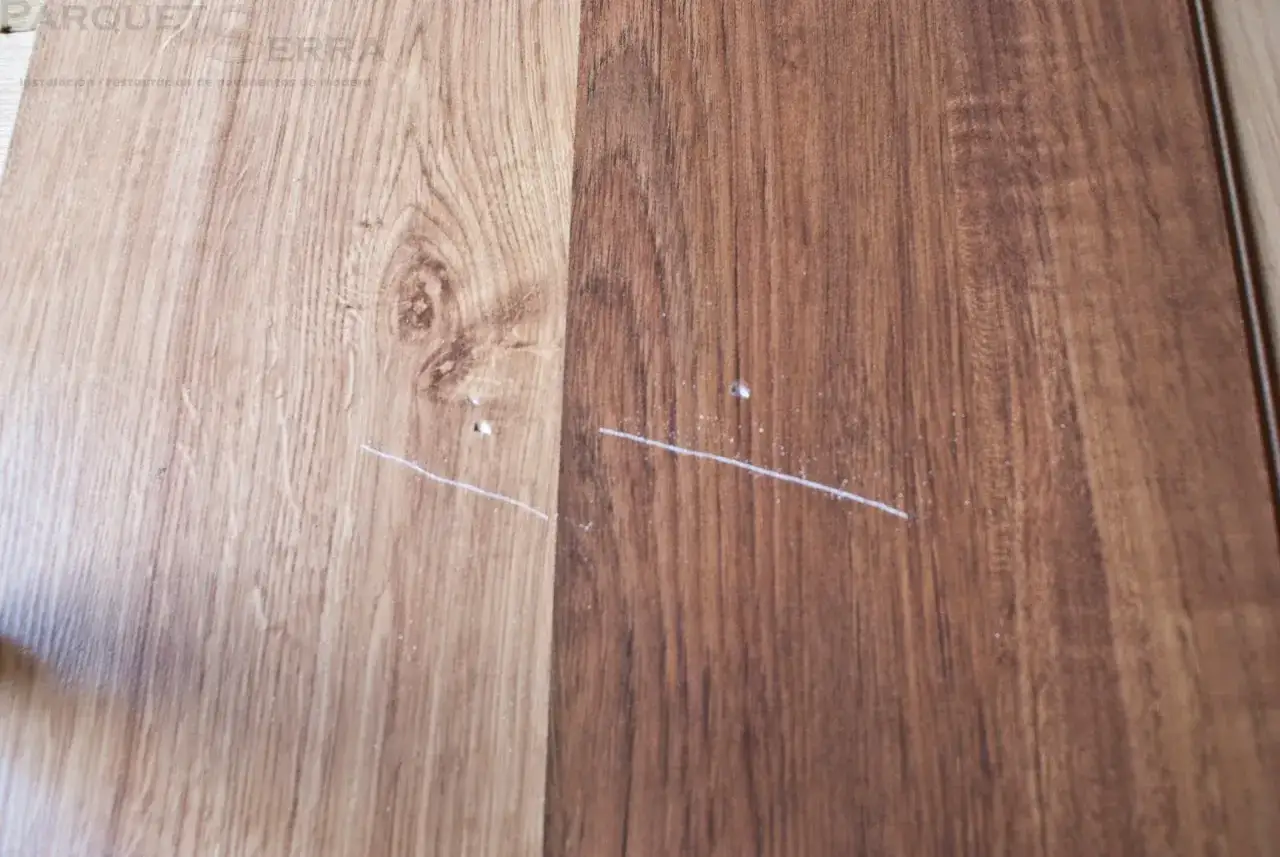 Dos tablones de parquet, uno claro y otro oscuro, muestran ara&ntilde;azos blancos. Busca remedios caseros para reparar parquet y devolverle su brillo.