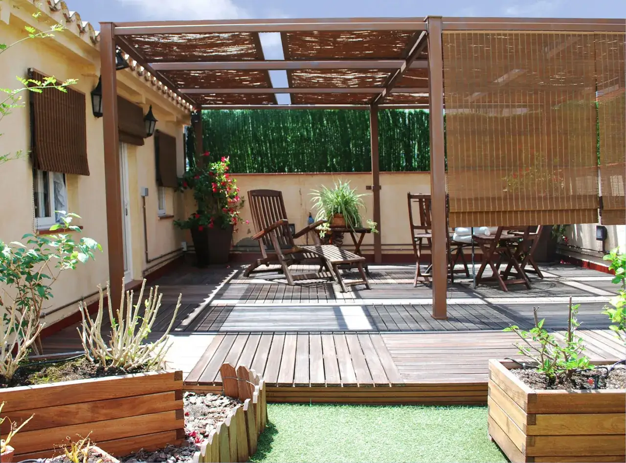 Terraza con pérgola, muebles de madera y jardineras con palets.