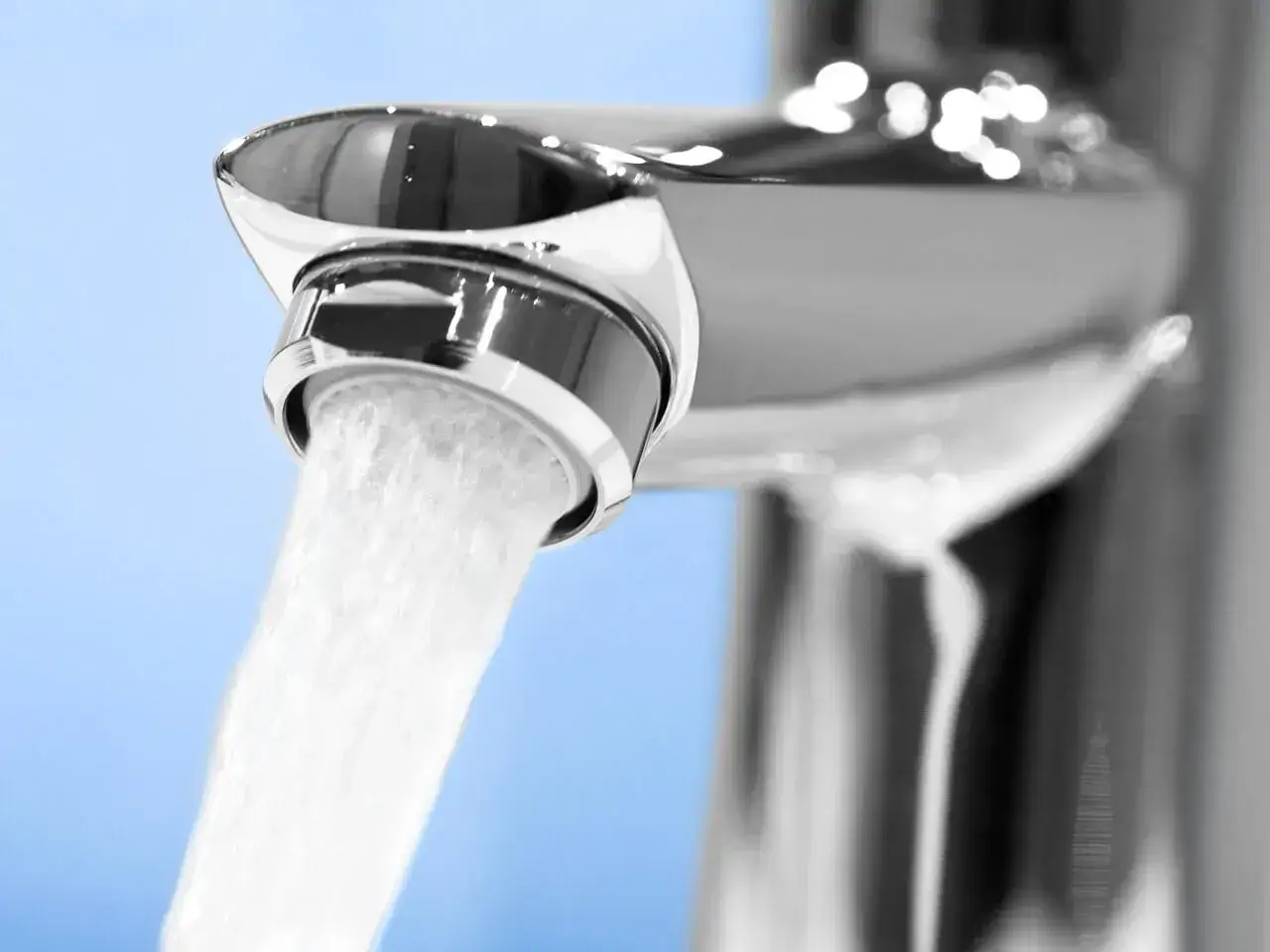 Primer plano de un grifo cromado con agua saliendo, mostrando uno de los tipos de aireadores para grifos que mezclan aire y agua.