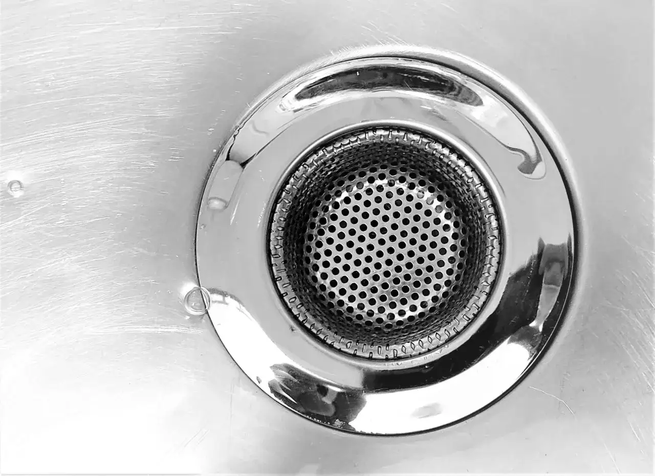 Primer plano de un desag&uuml;e de ducha met&aacute;lico con rejilla perforada. Ideal para desatascar desag&uuml;e ducha y mantener el agua fluyendo.