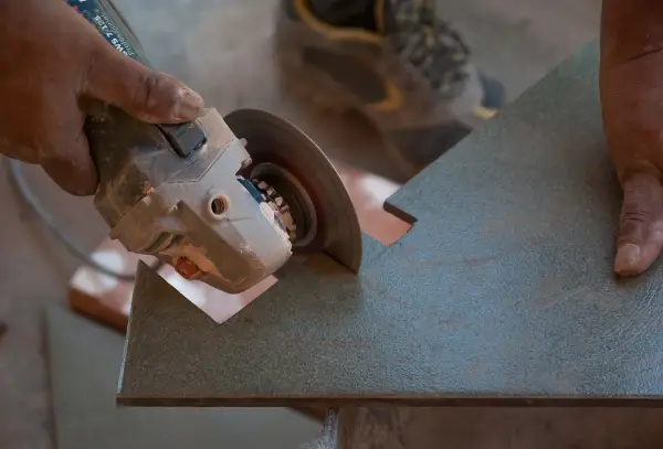 Mano sujetando una radial para cortar azulejos con precisión.