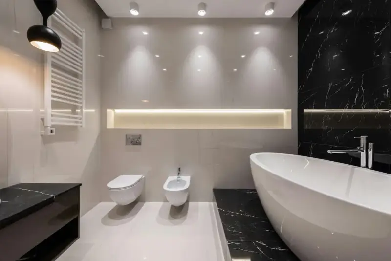 Radiador toallero blanco colgado en pared junto a un inodoro y bidet, ideal para baños modernos.